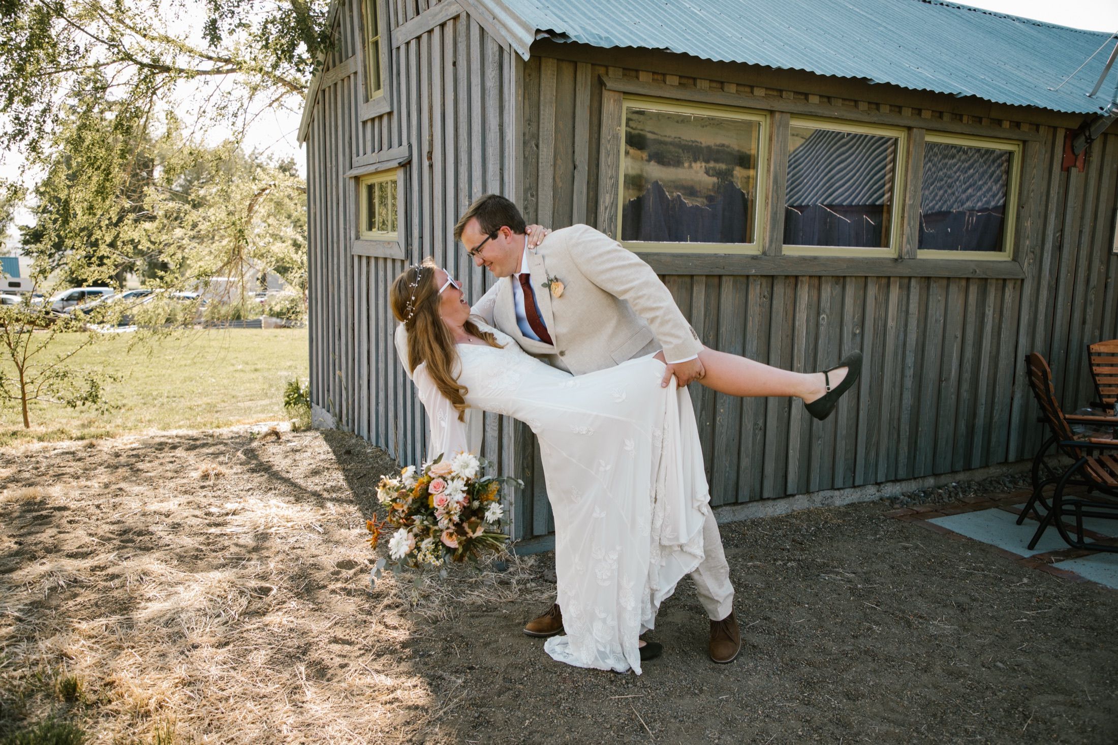 Reuben dipping Meghan in his arms outside a wood-sided barn.