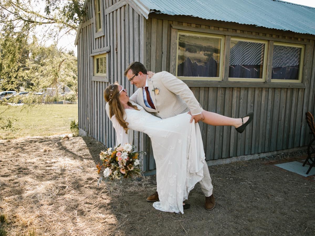 Reuben dipping Meghan in his arms outside a wood-sided barn.