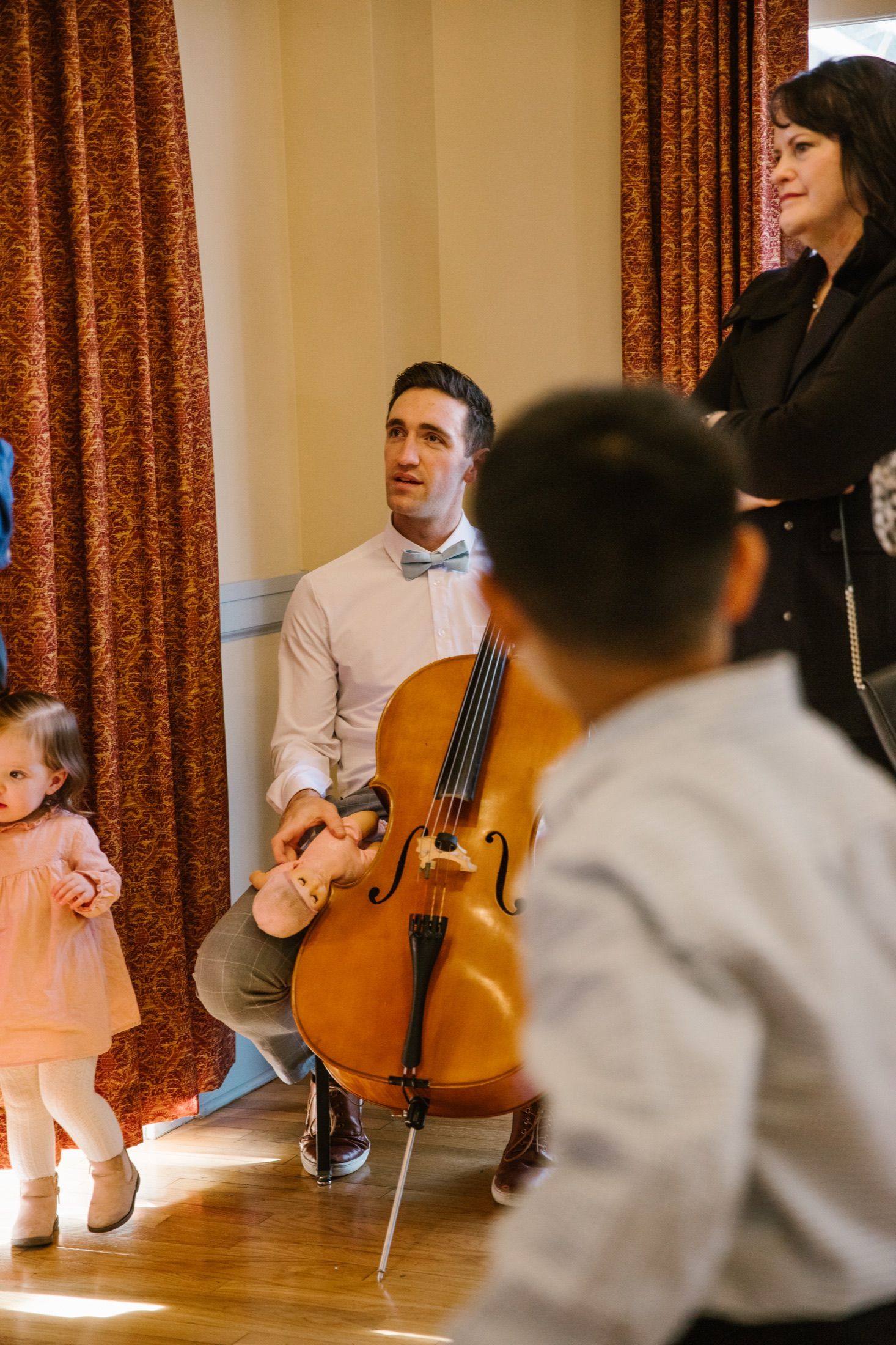 A cellist plays at Brandon and Gabi's wedding while a child watches.