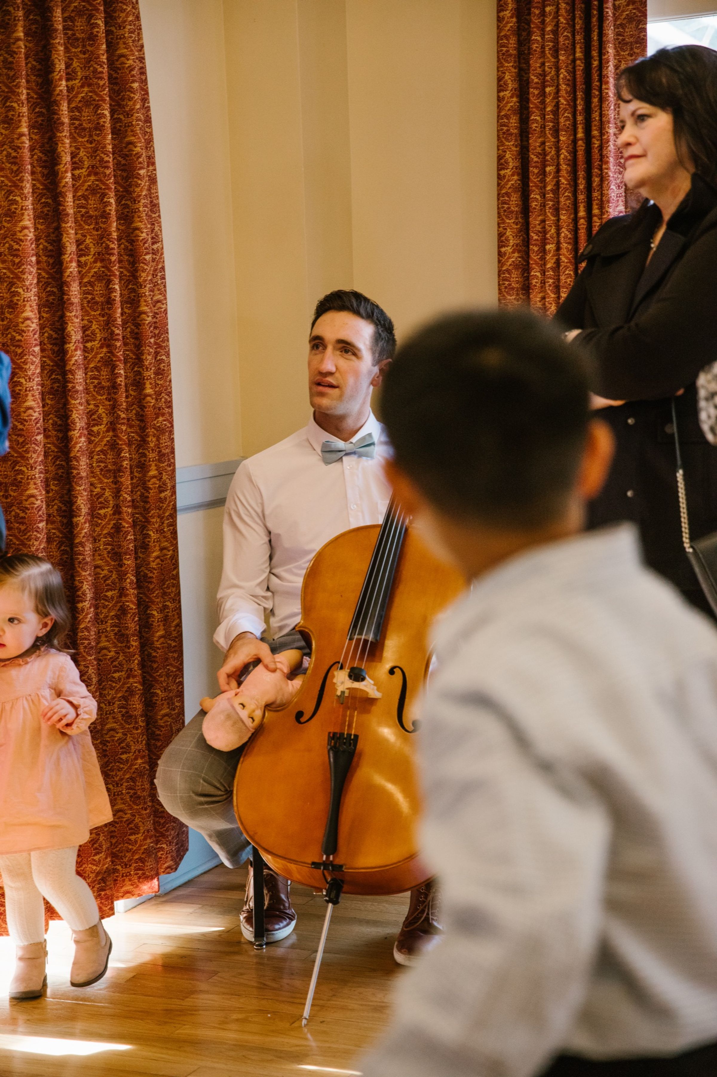 A cellist plays at Brandon and Gabi's wedding while a child watches.