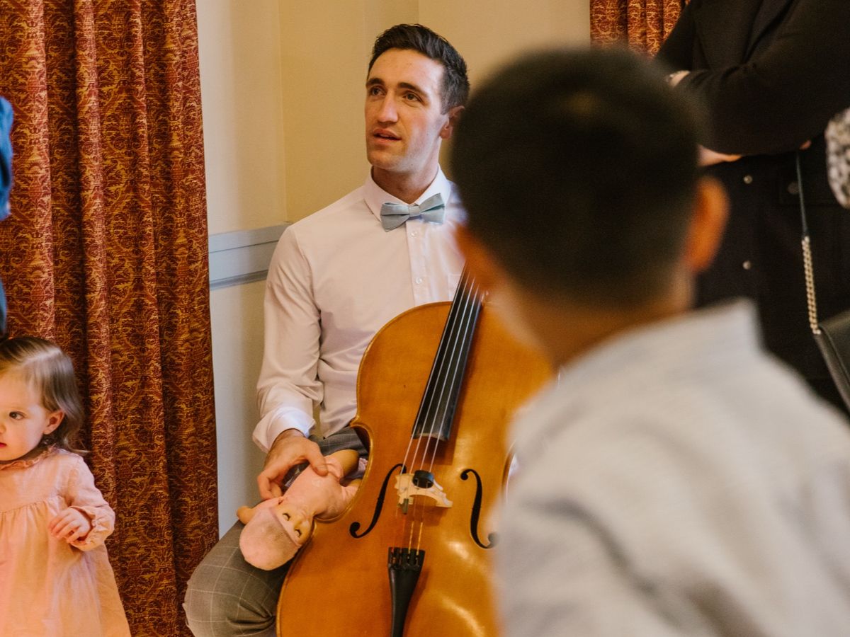 A cellist plays at Brandon and Gabi's wedding while a child watches.