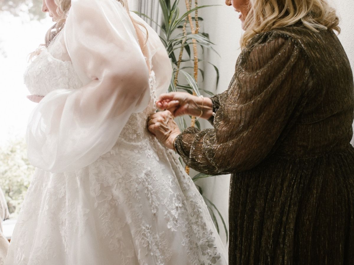 Kenady's mother lacing the back of her wedding dress.