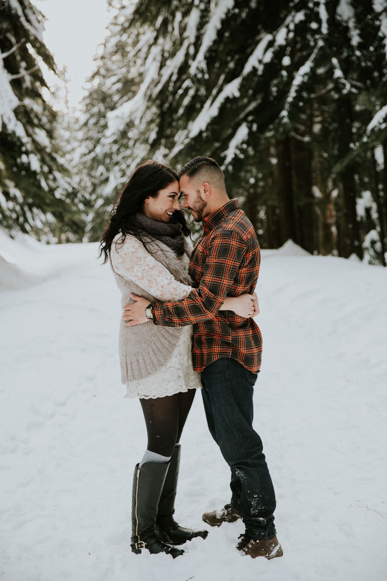 Kaitlyn and Evan in a snowy Cascade forest, foreheads pressed together.
