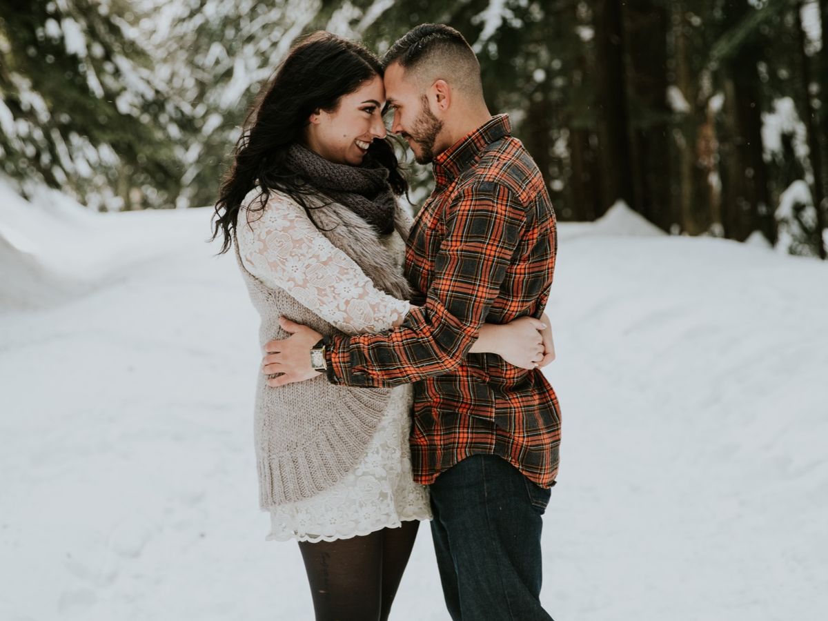 Kaitlyn and Evan in a snowy Cascade forest, foreheads pressed together.
