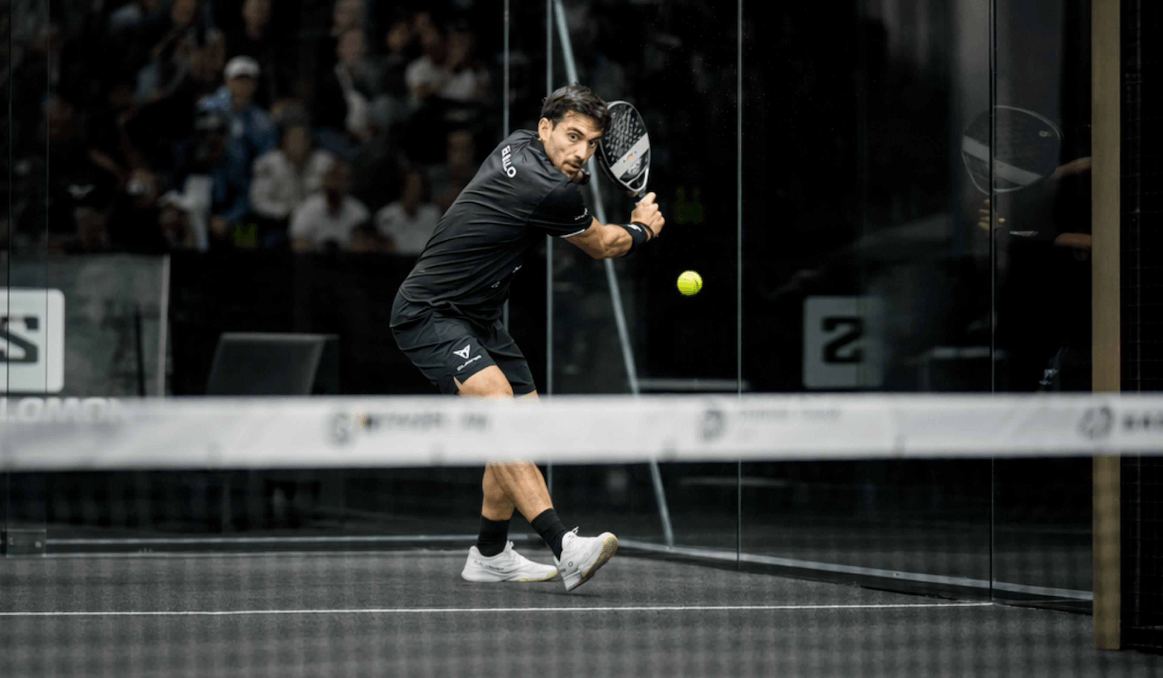 Padel player hitting off the back glass