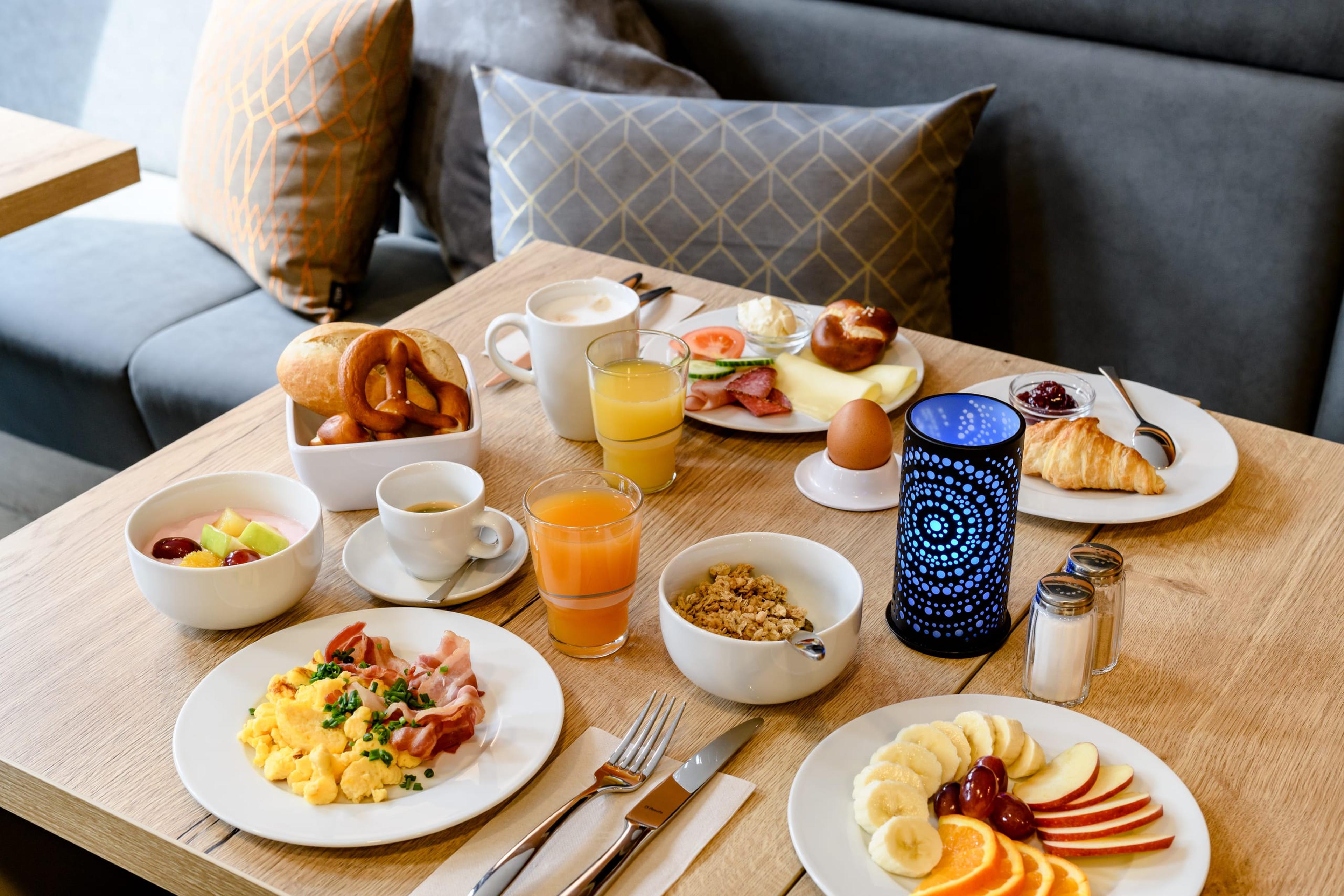 Reich gedeckter Frühstückstisch mit Croissants, Kaffee und Obst