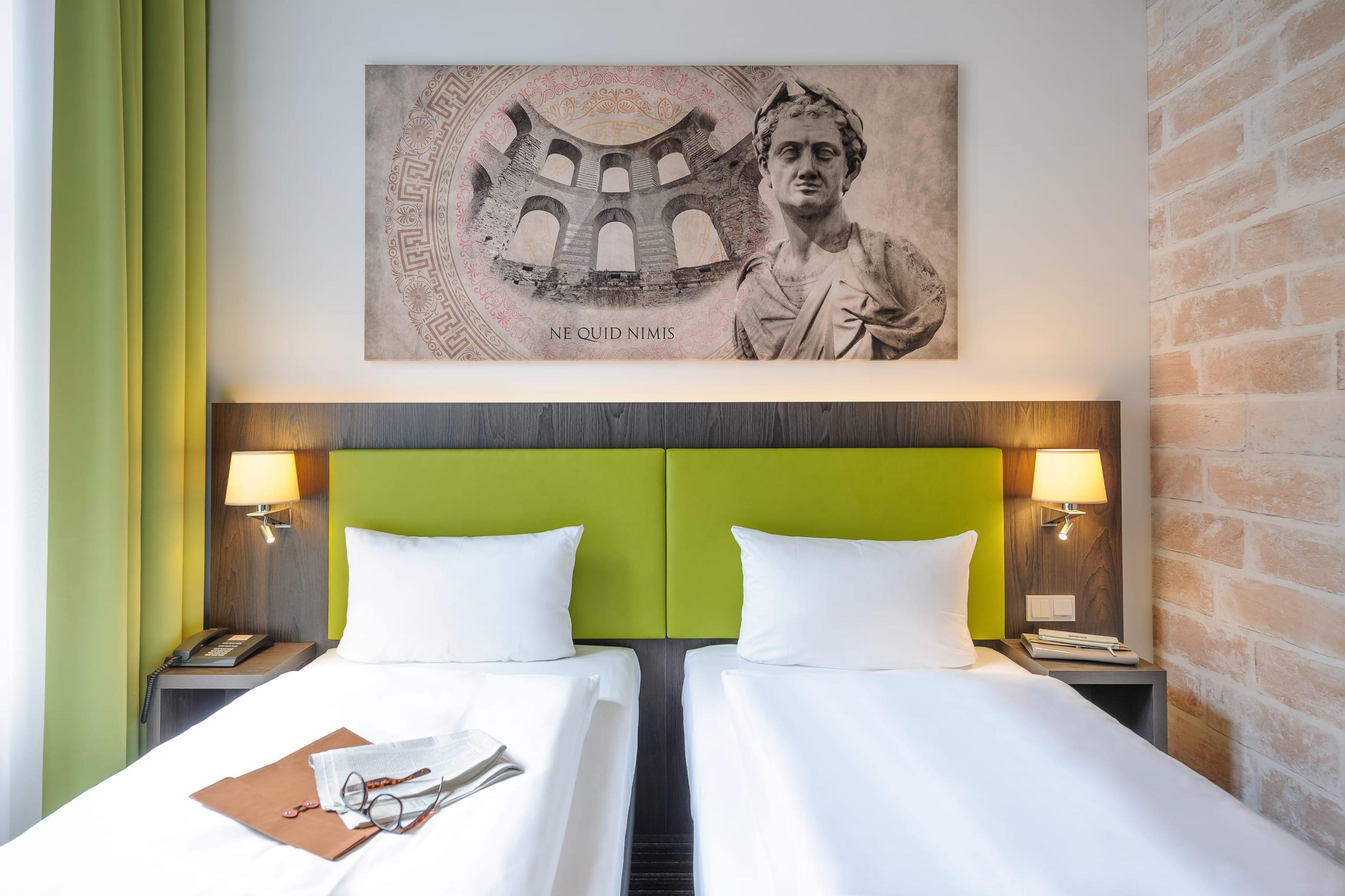 Hotelzimmer mit Doppelbett und römischem Wandbild