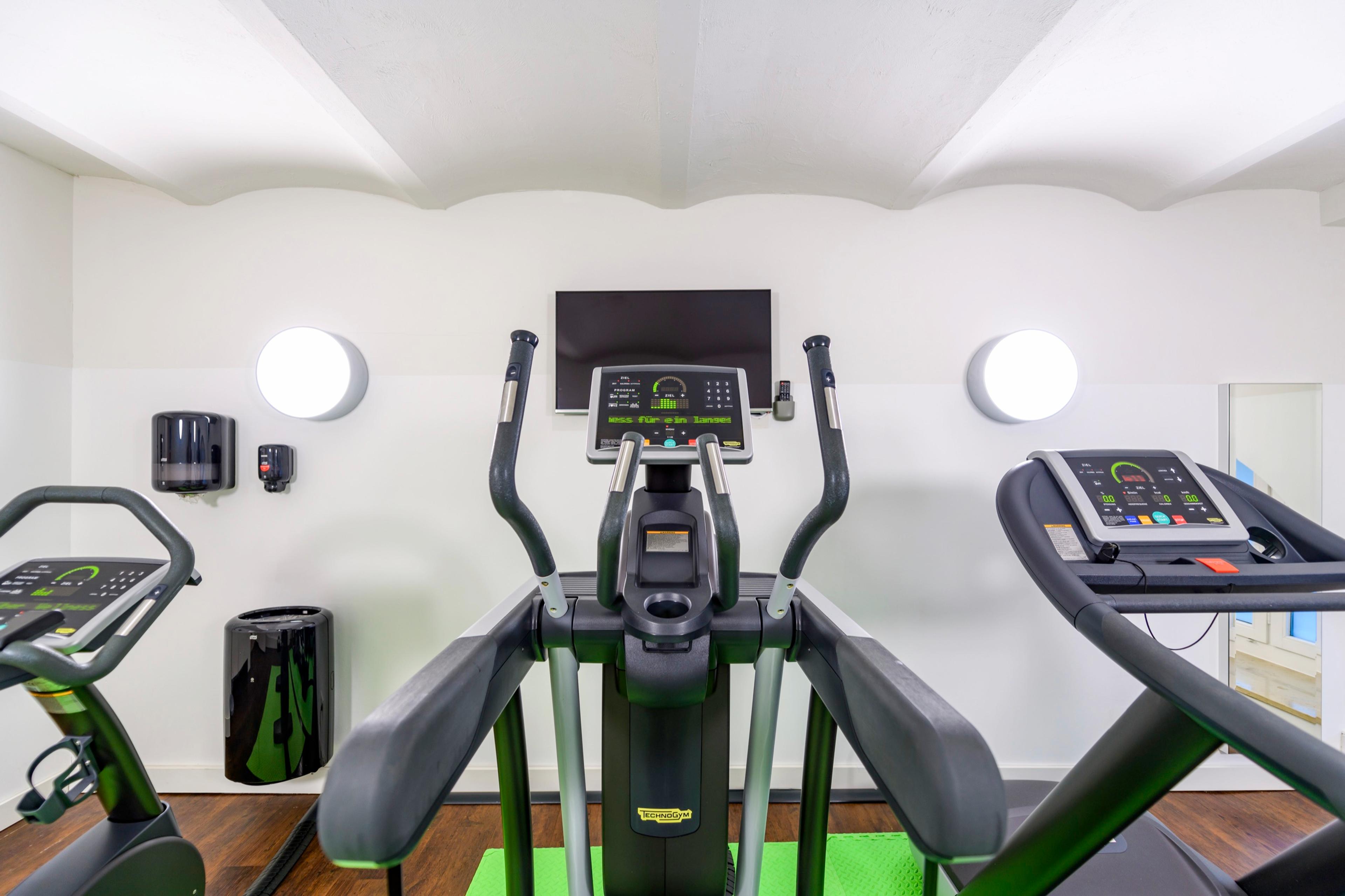 Fitnessbereich, Crosstrainer mit Konsole und Wandleuchten