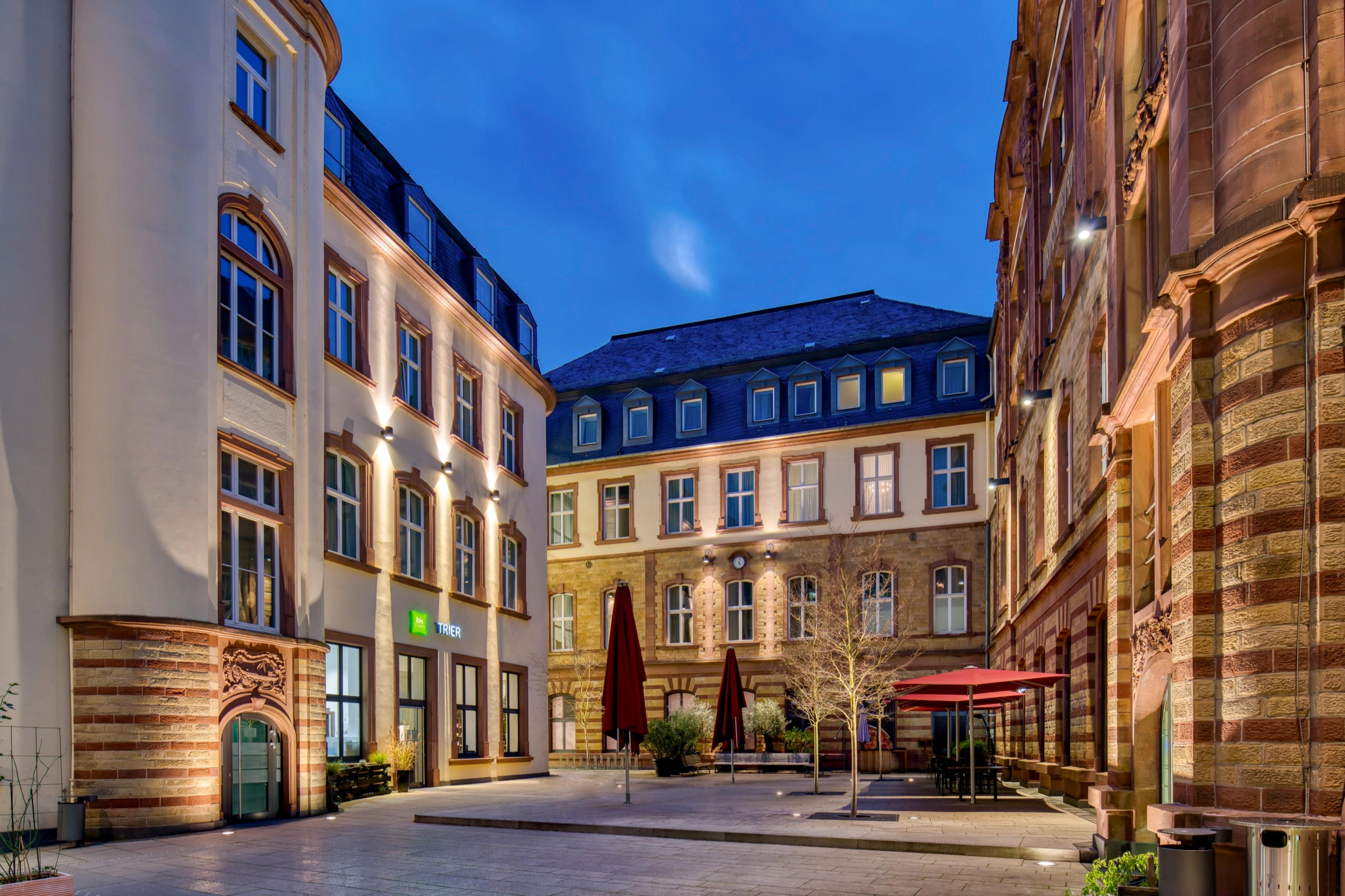 Posthof-Innenhof zur blauen Stunde mit roten Sonnenschirmen