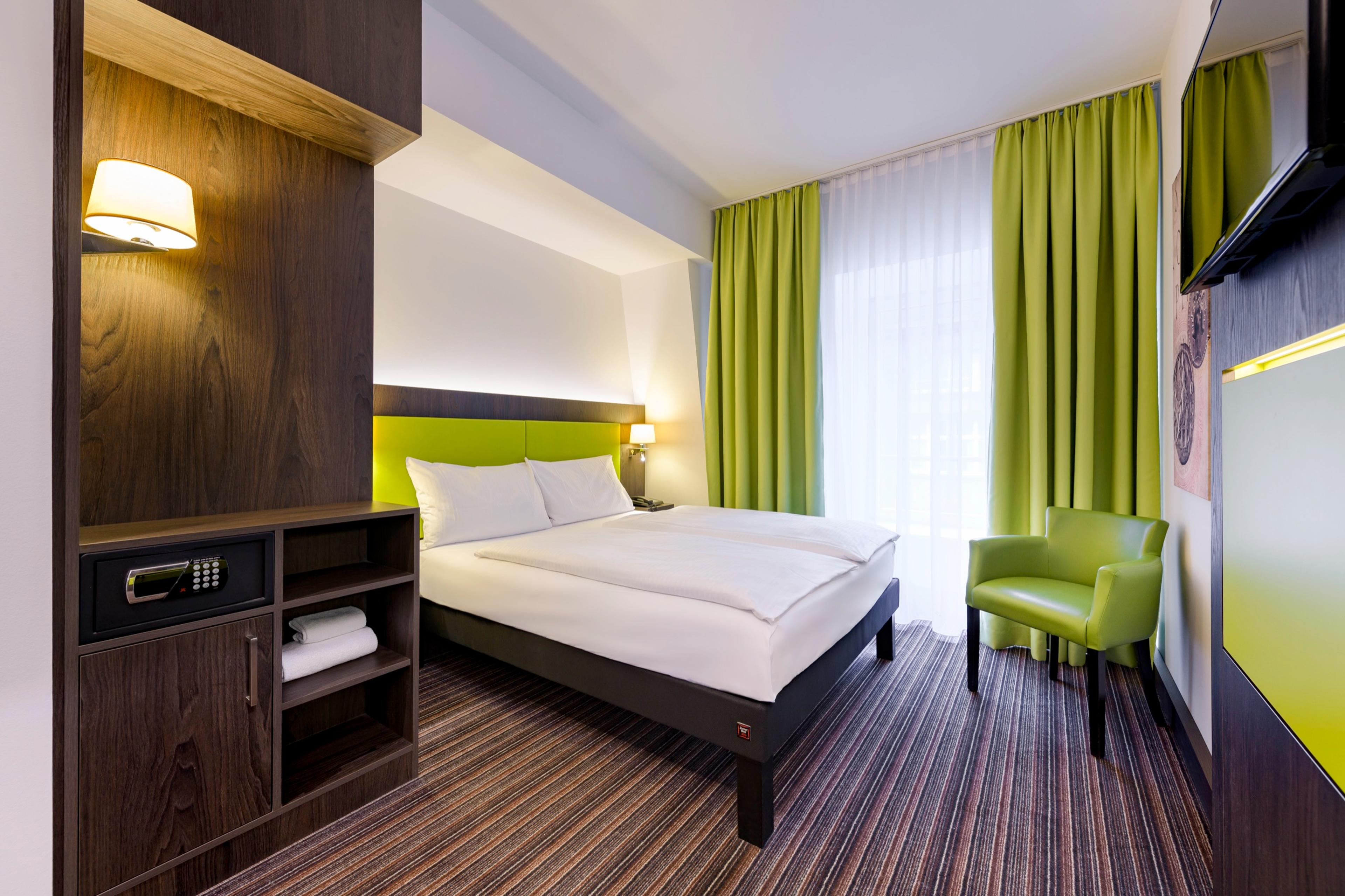 Comfort-Zimmer mit Doppelbett, grünem Sessel und Safe