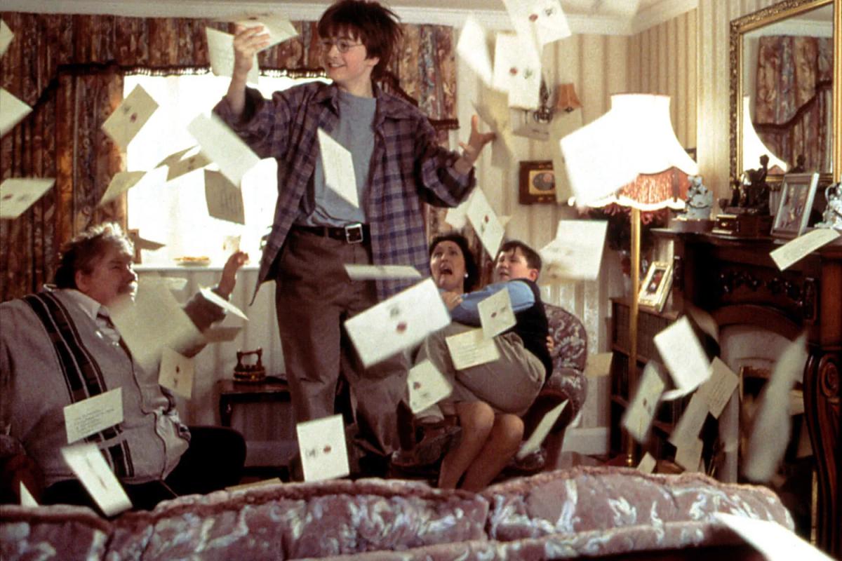 Harry Potter (Daniel Radcliffe) leaps for a Hogwarts letter as hundreds of them pour into the Dursleys' living room and the family takes cover.