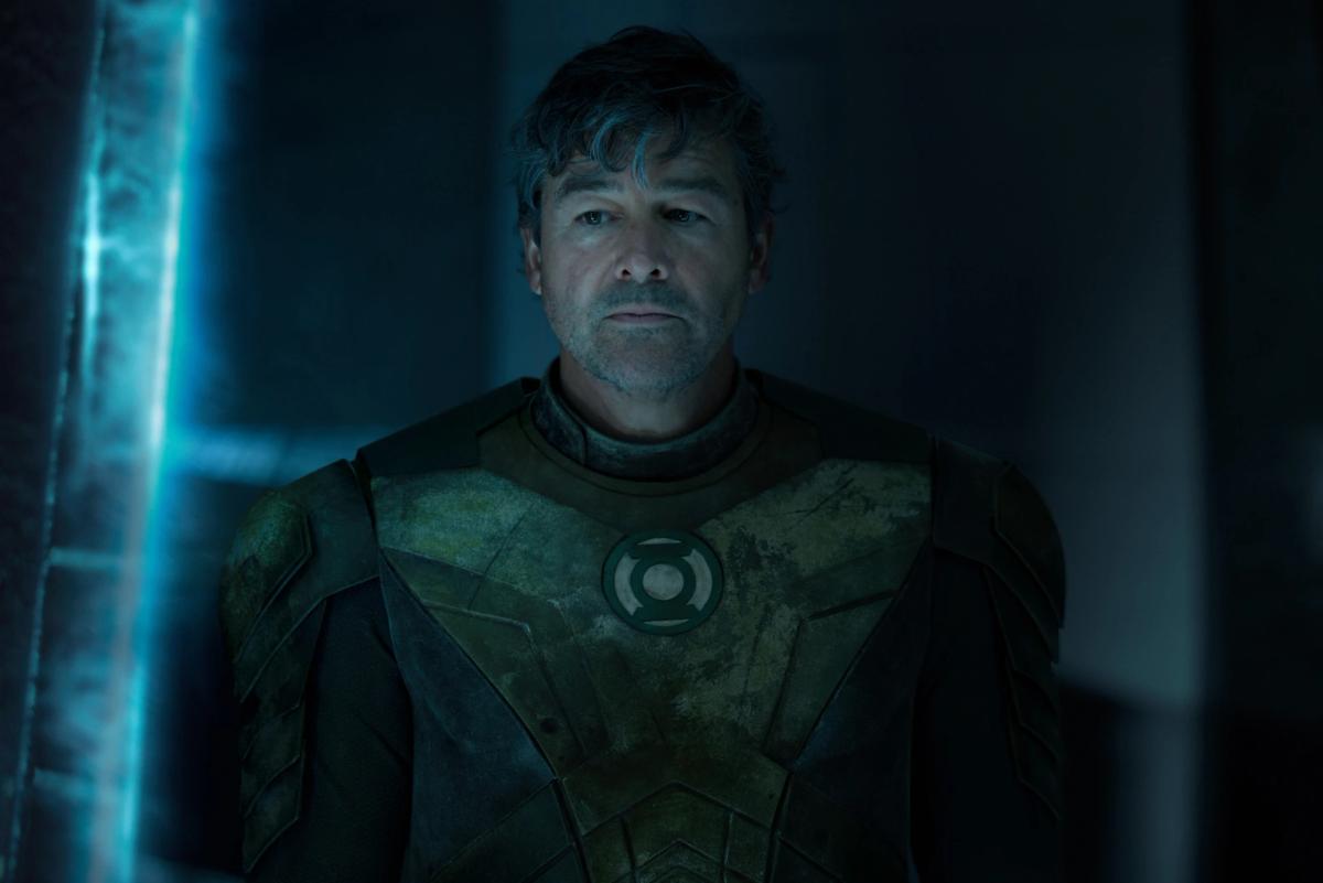 Kyle Chandler as Hal Jordan in the Green Lantern uniform, lit in blue, looking directly at camera.
