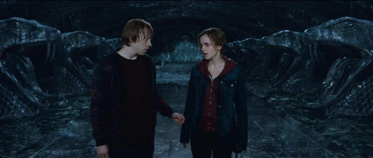 Rupert Grint as Ron Weasley and Emma Watson as Hermione Granger stand facing each other in the Chamber of Secrets.