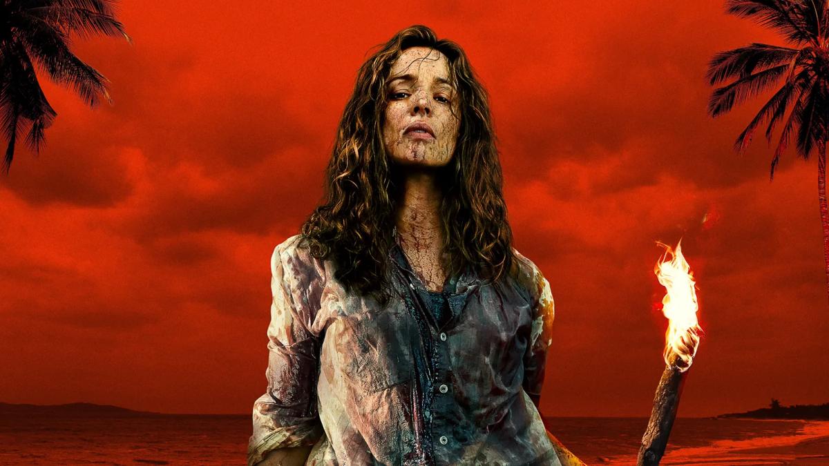 Rachel McAdams as Linda Liddle kneels over Dylan O'Brien as Bradley Preston on the beach, holding a coconut shell of water to his cut face, both soaked after the crash.