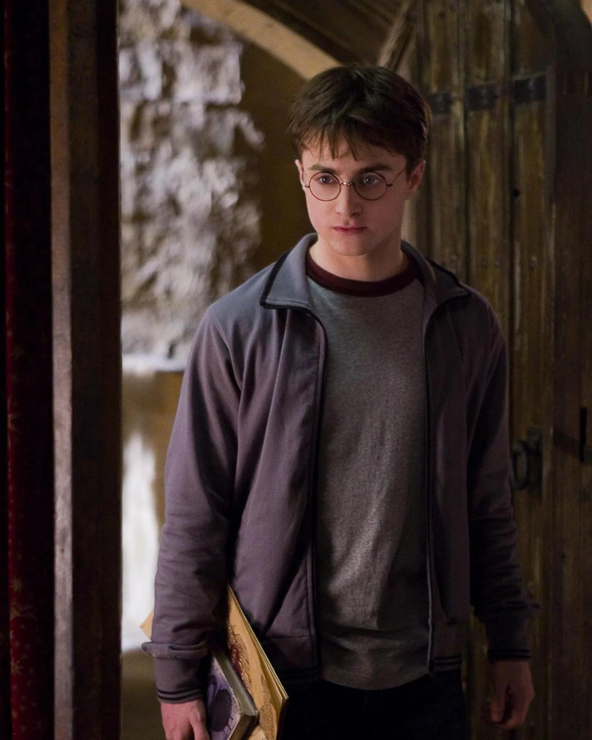 Daniel Radcliffe as Harry Potter holding his copy of Advanced Potion-Making in the dormitory