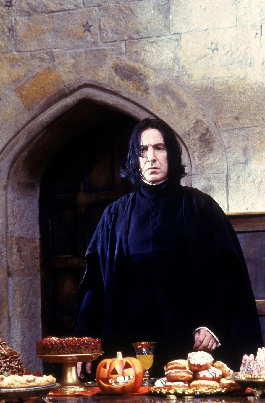 Severus Snape (Alan Rickman) standing alone at the far end of the Great Hall behind the Halloween feast.