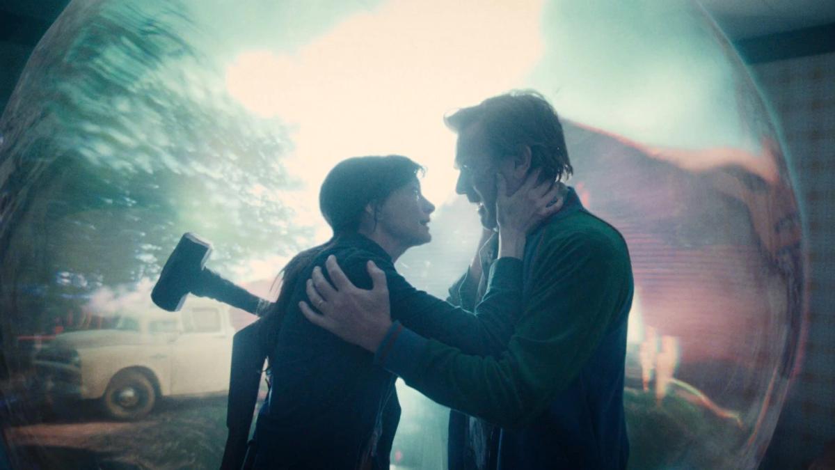 Denise and Greg Platt hold each other inside a shimmering spherical distortion, a parked truck visible through its wall behind them.