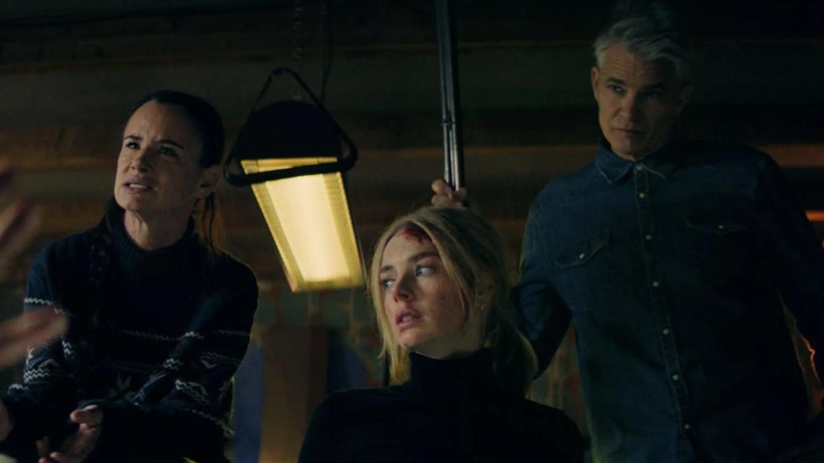 Juliette Lewis as Allegra and a bloodied Samara Weaving as Lisa lit by a hanging lantern, with an armed man behind them.