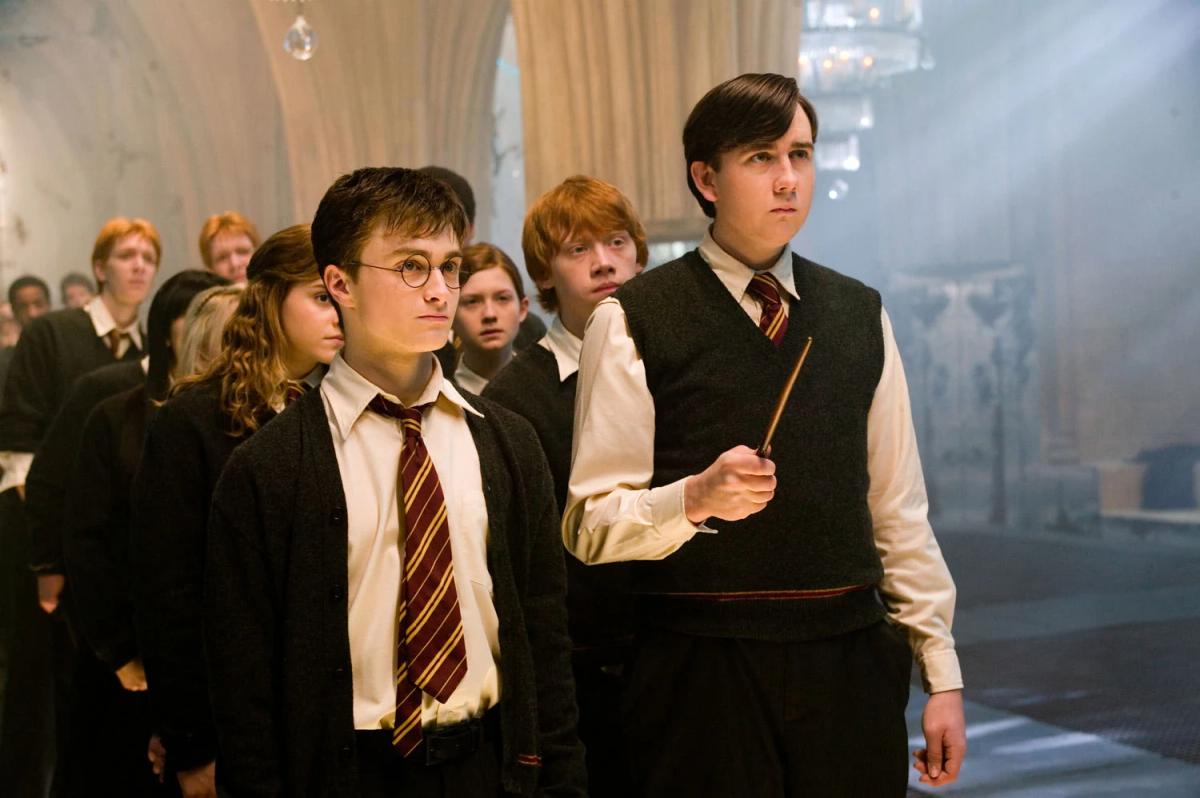 Harry Potter (Daniel Radcliffe) holds his wand out during a Dumbledore's Army lesson, with Ron Weasley (Rupert Grint) and Neville Longbottom (Matthew Lewis) beside him.