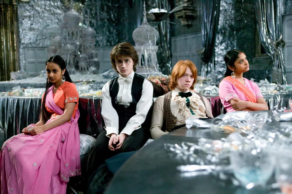 Daniel Radcliffe as Harry Potter and Rupert Grint as Ron Weasley sit at a Yule Ball table between their dates, the Patil sisters, played by Shefali Chowdhury and Afshan Azad.