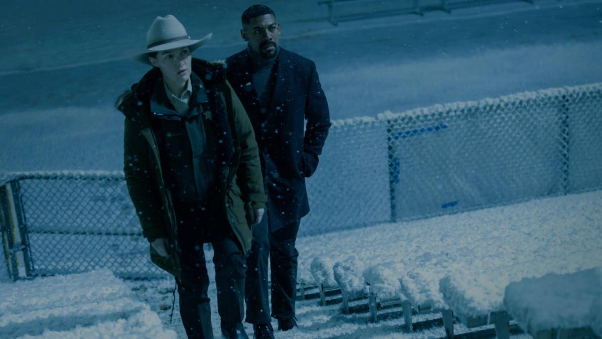 Aaron Pierre as an older John Stewart and Kelly Macdonald as Sheriff Kerry Kane walking through snow at the Rushville football field in 2026