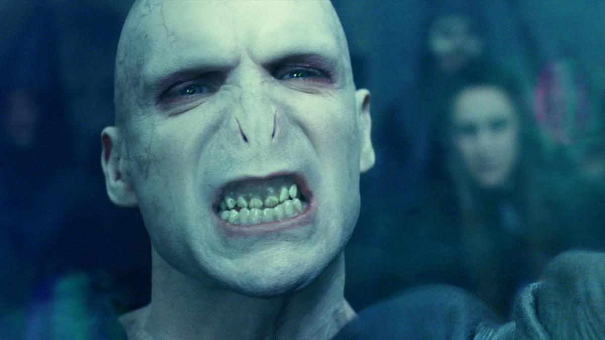 Ralph Fiennes as Lord Voldemort, pale and noseless, bares his teeth in close-up.