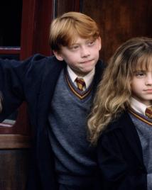 Daniel Radcliffe as Harry Potter, Rupert Grint as Ron Weasley and Emma Watson as Hermione Granger lean out of a Hogwarts Express door.