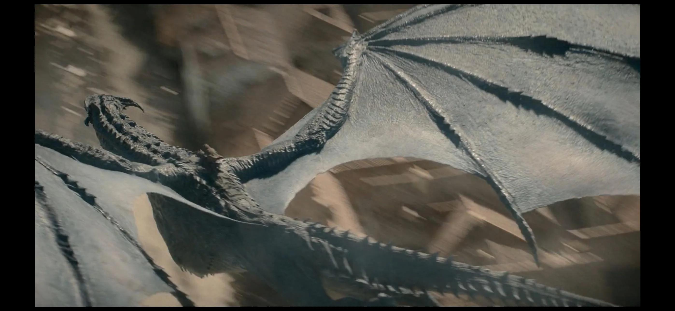 A pale silver dragon banking hard over rooftops, one wing fully extended and its tail curling beneath it
