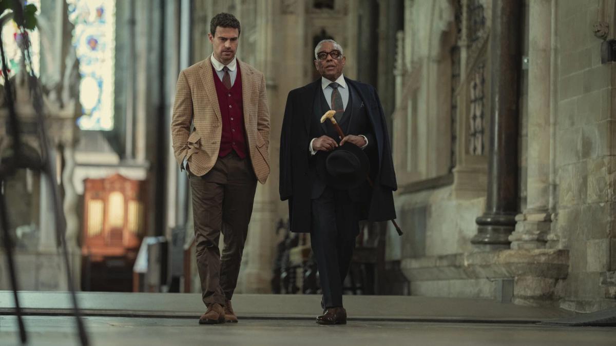Theo James as Eddie Horniman walking a cathedral nave beside Giancarlo Esposito as Stanley Johnston, who carries a cane and hat.