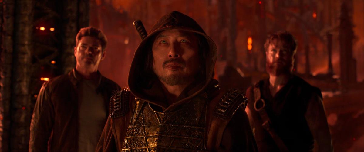 Karl Urban as Johnny Cage, Hiroyuki Sanada as a hooded Scorpion, and Josh Lawson as Kano in the red glow of the Netherrealm.