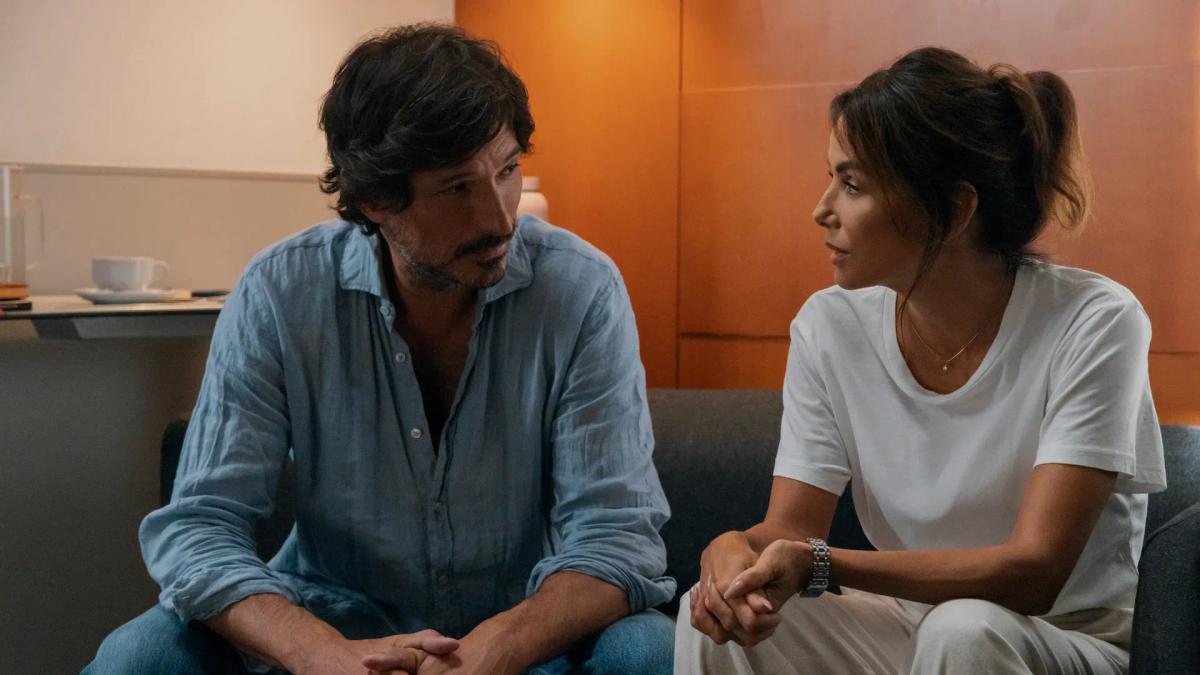 Andrés Velencoso as Mateo García and Eva Longoria as Isolde Pera sitting together on a sofa in conversation.