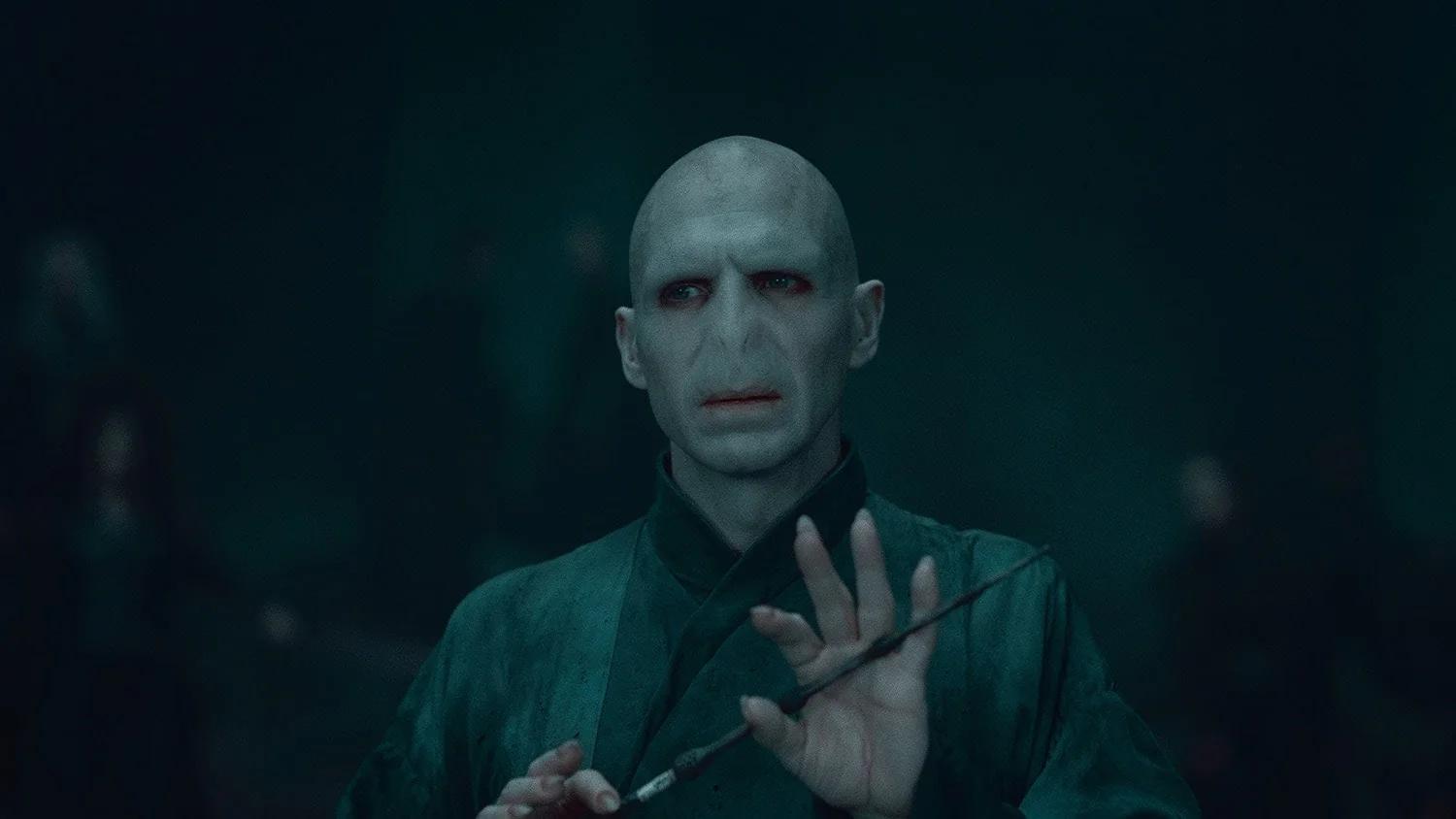 Ralph Fiennes as Lord Voldemort holds the Elder Wand across his hands.