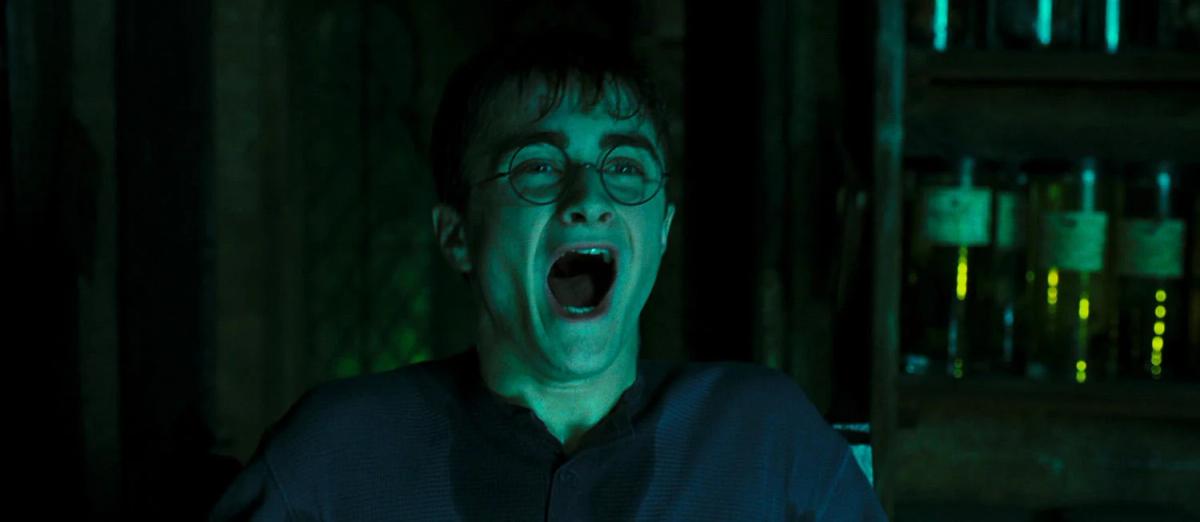 Harry Potter (Daniel Radcliffe) shouting, lit in cold green light, during an Occlumency lesson.