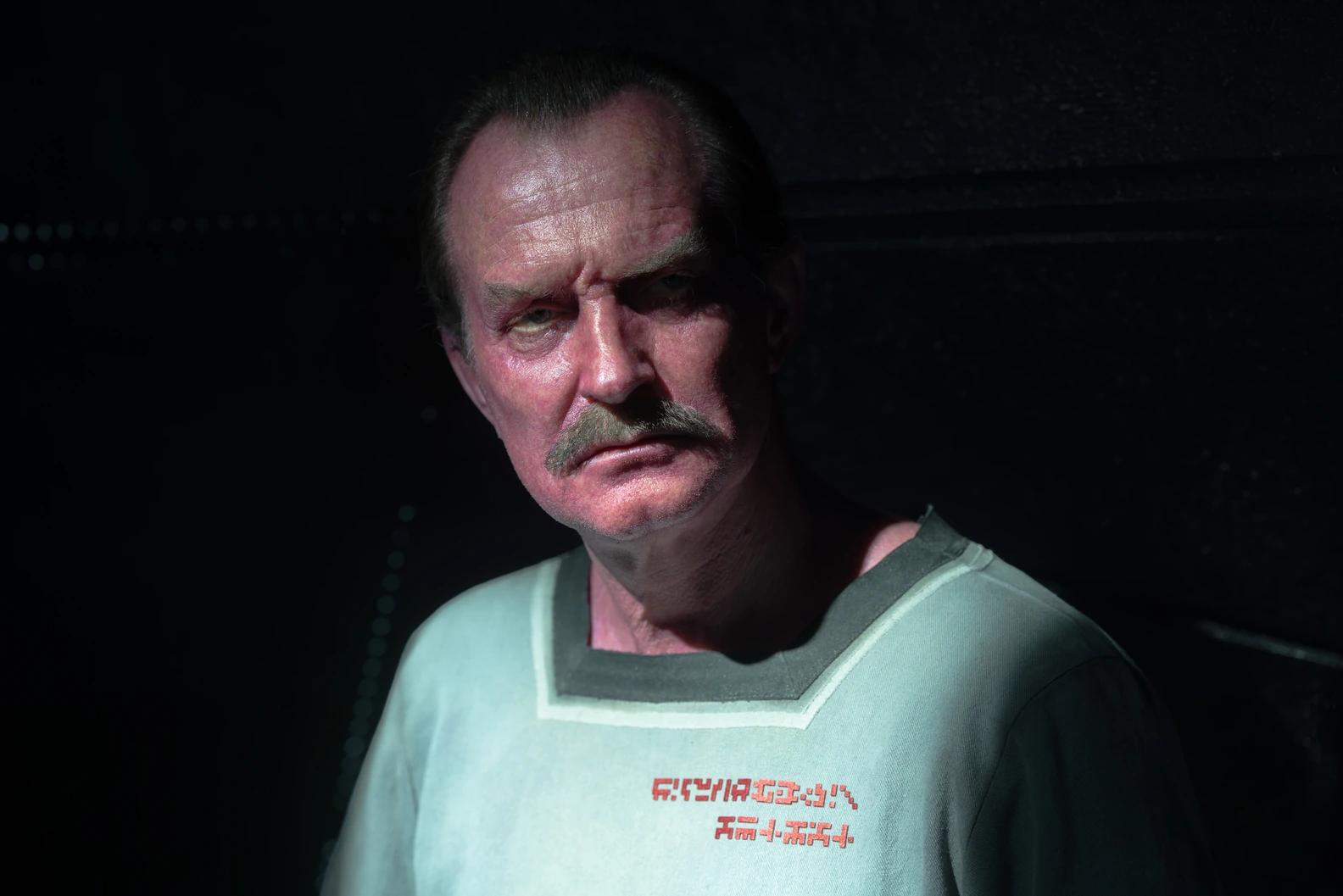Ulrich Thomsen as the imprisoned Sinestro in Lanterns Episode 2, lit from one side in prison clothing marked with alien script.