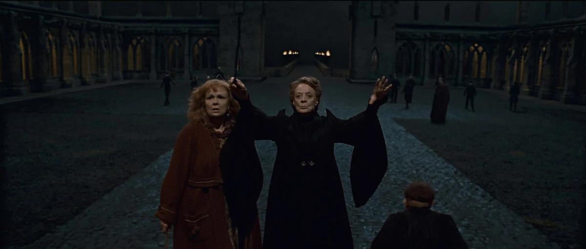 Maggie Smith as Minerva McGonagall standing in a Hogwarts courtyard with both arms raised, Julie Walters as Molly Weasley beside her.
