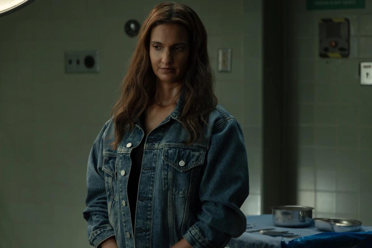 Poorna Jagannathan as Zoe Macon standing in a hospital operating room.