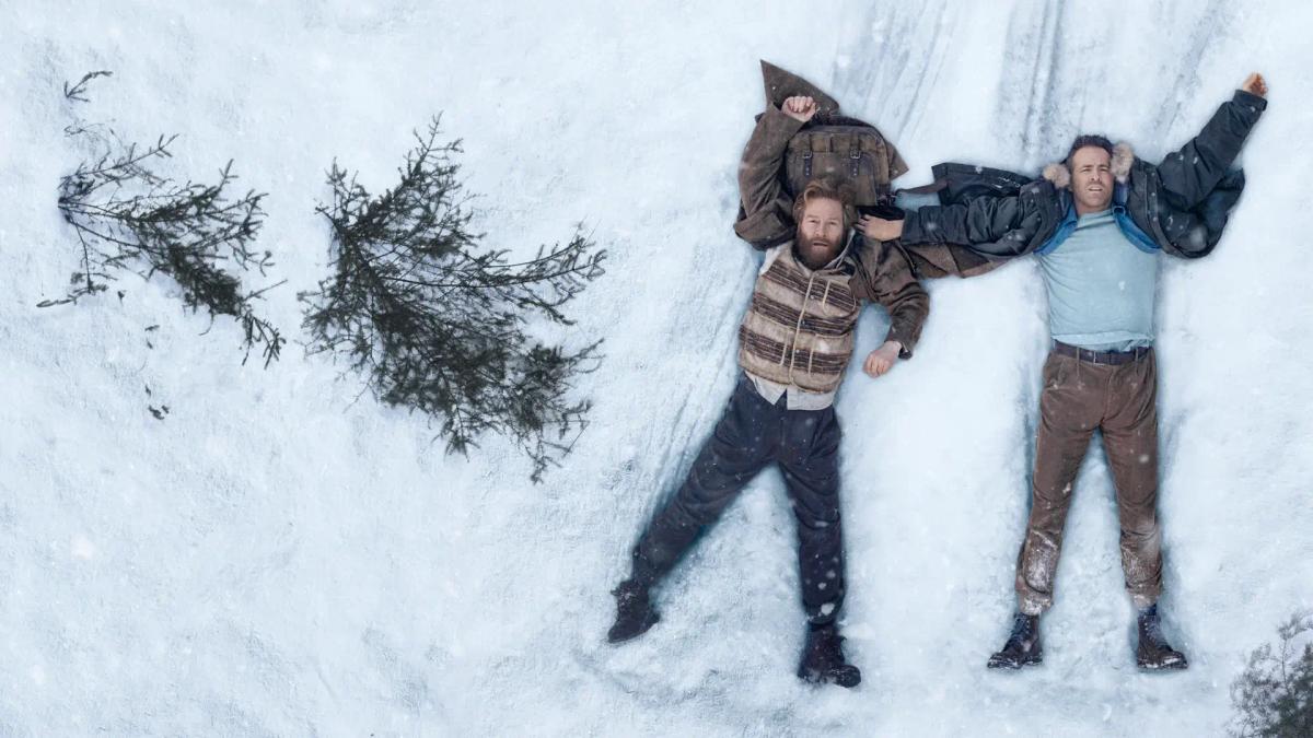 Overhead shot of Ryan Reynolds as Troy Kelly and Kenneth Branagh as Nikolai Ustinov lying spread out in deep snow