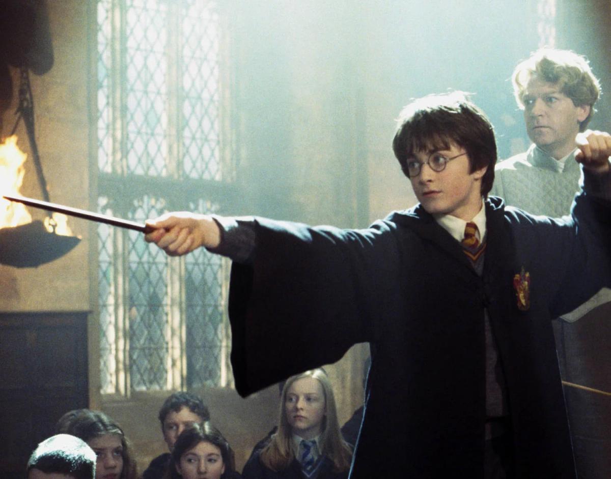 Daniel Radcliffe as Harry Potter points his wand with Kenneth Branagh as Gilderoy Lockhart behind him at the Duelling Club.