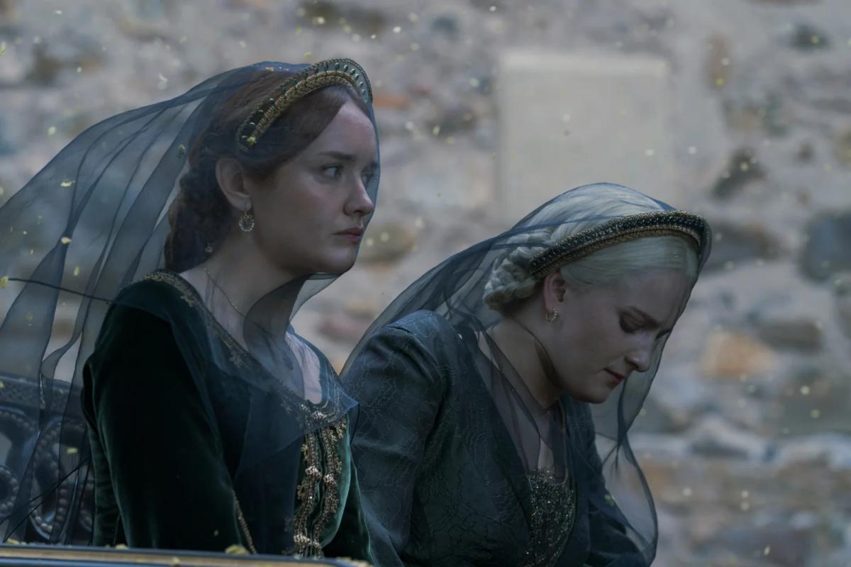 Olivia Cooke as Alicent Hightower and Phia Saban as Helaena Targaryen in black mourning veils, petals falling around them