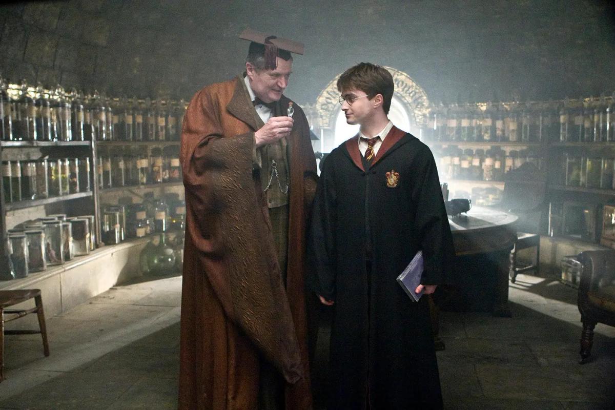 Jim Broadbent as Horace Slughorn presents Felix Felicis to Daniel Radcliffe as Harry Potter in the Potions classroom.