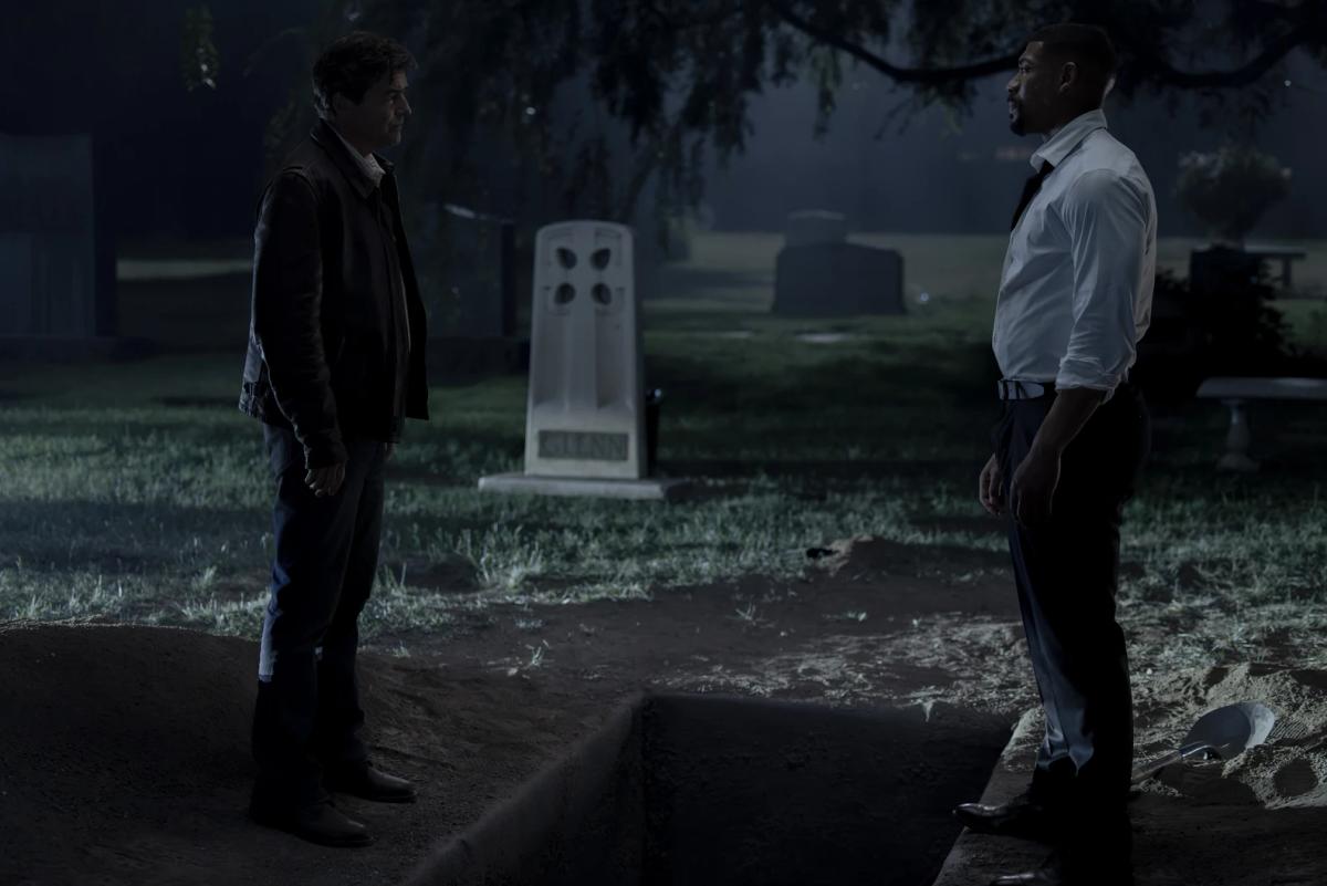 Kyle Chandler as Hal Jordan's Halogram standing at night in a foggy cemetery, facing Aaron Pierre as John Stewart.