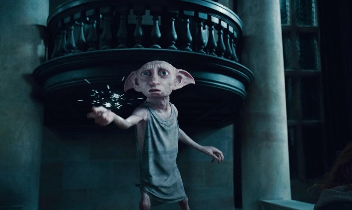 Dobby stands on the balcony landing at Malfoy Manor gripping the fixture of the chandelier he is about to bring down.