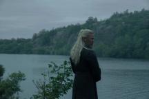 Hugh Hammer standing alone by a river in dark clothing, looking back over his shoulder