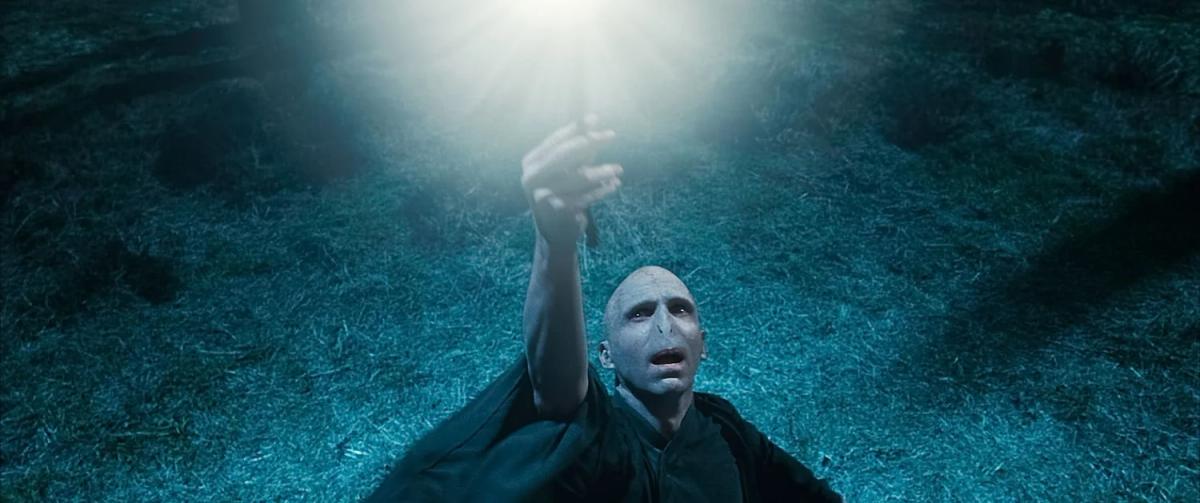 Ralph Fiennes as Lord Voldemort raises the Elder Wand above his head.