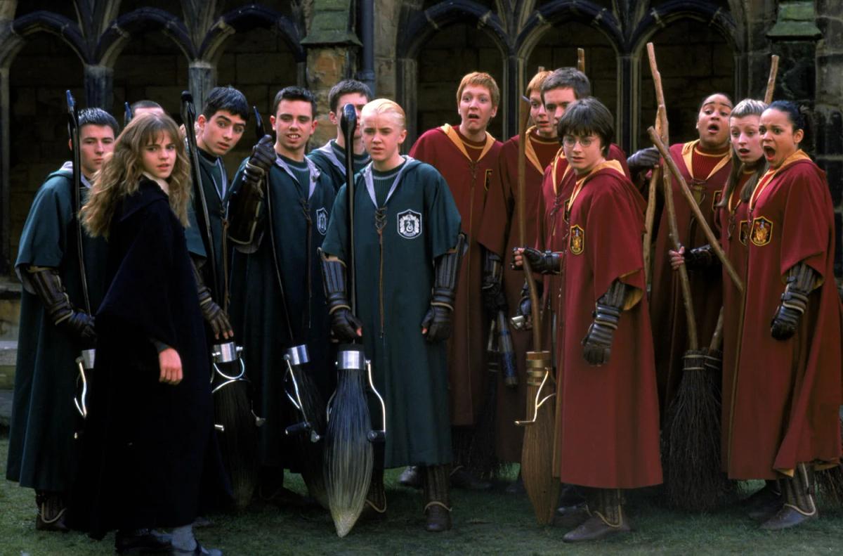 Hermione Granger (Emma Watson) faces the Slytherin team holding new Nimbus 2001 brooms, Draco Malfoy (Tom Felton) at their centre, with the Gryffindor team reacting on the right.