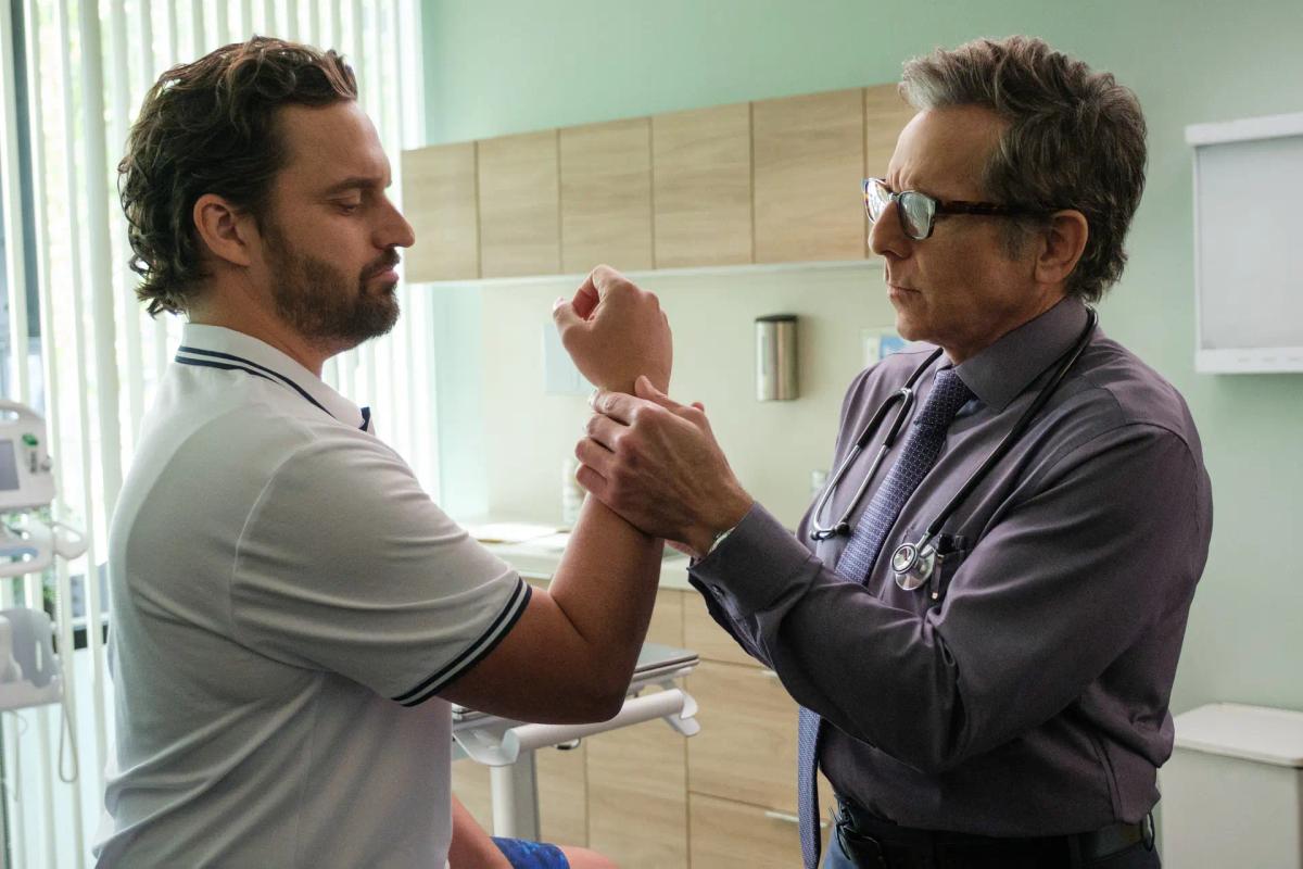 Dusty Boyd (Jake Johnson) has his wrist flexed and examined by Dr. Stone (Ben Stiller) in a consulting room.
