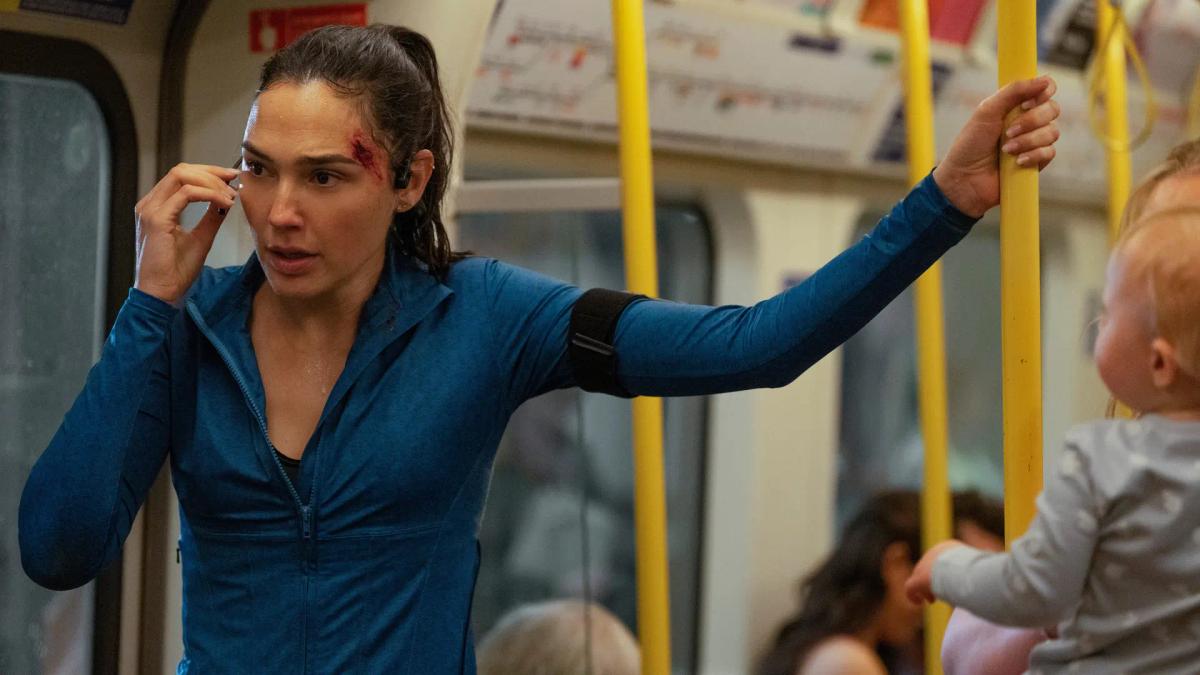 Maia Marten holds a pole in a crowded Underground carriage, touching her earpiece, passengers around her paying no attention.