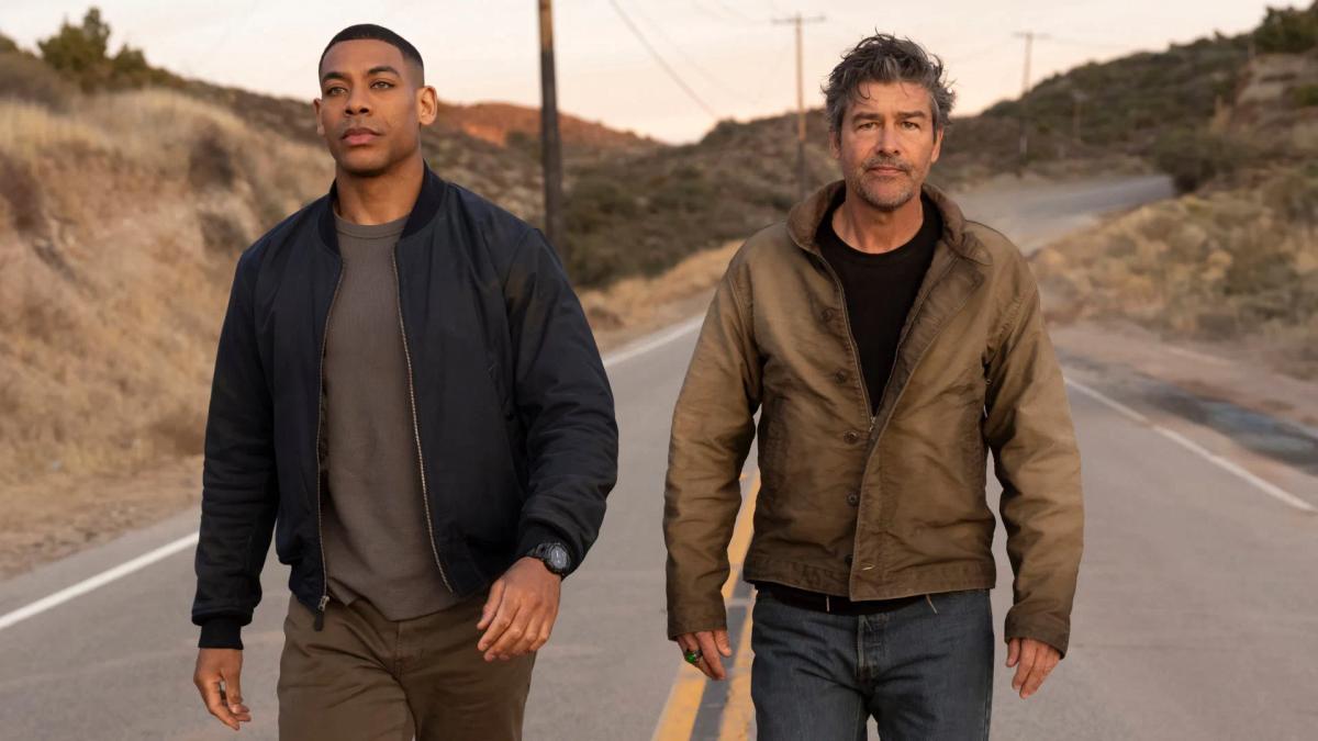 Aaron Pierre as John Stewart and Kyle Chandler as Hal Jordan walk down a rural highway in Lanterns episode 1
