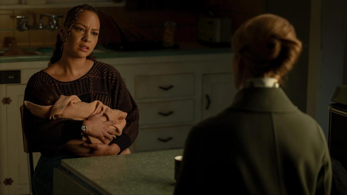 Jasmine Cephas Jones as Bernadette Stewart holding her baby at a kitchen table, talking to Laura Linney's Guardian.