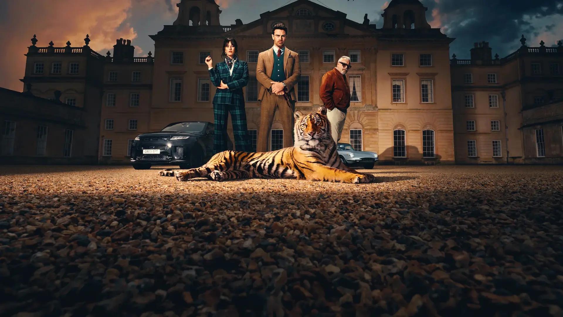 Kaya Scodelario as Susie Glass, Theo James as Eddie Horniman and Ray Winstone as Bobby Glass standing outside Halstead Manor at dusk behind a full-grown tiger lying on the gravel.